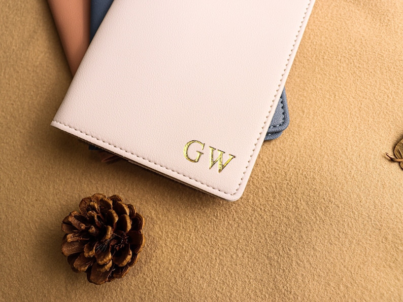 May include: A pink leather journal with gold lettering that reads "GW" on the front cover.