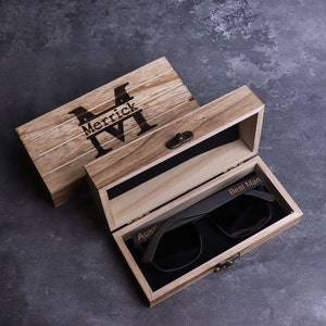 May include: A wooden box with a personalised inscription "Merrick M" on the lid. The box is open and contains a pair of black sunglasses with the inscription "Best Man" on the frame.