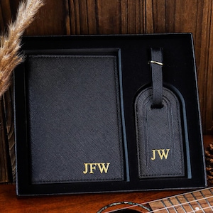 K&ouml;nnte beinhalten: Schwarzes Leder-Reisepass-Etui und Gep&auml;ckanh&auml;nger-Set mit goldener Beschriftung. Das Reisepass-Etui tr&auml;gt die Initialen "JFW" und der Gep&auml;ckanh&auml;nger die Initialen "JW".