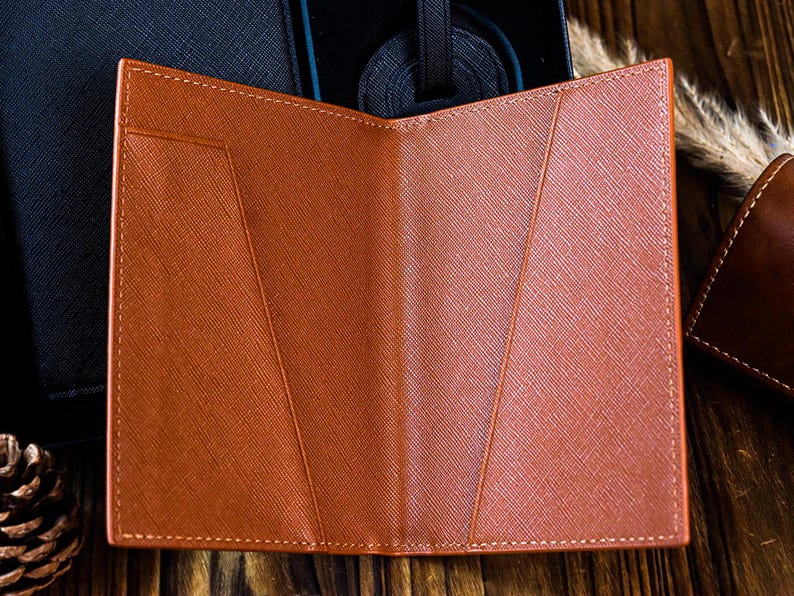 K&ouml;nnte beinhalten: Ein brauner Leder-Reisepass-Etui mit mehreren Kartenf&auml;chern und einem Klappverschluss. Das Etui ist ge&ouml;ffnet und das Innere ist sichtbar.