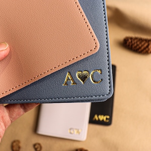 May include: A blue and pink leather passport holder with gold lettering that says "A&hearts;C".