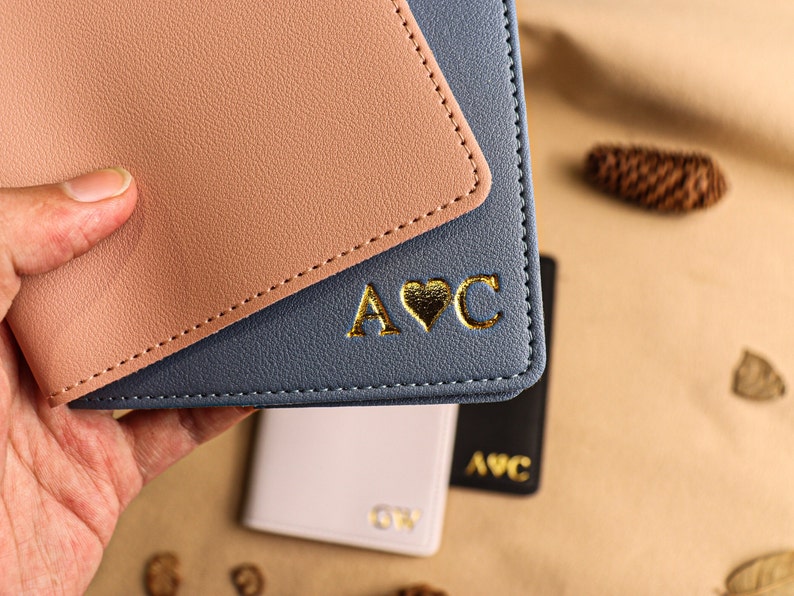May include: A blue and pink leather passport holder with gold lettering that says "A&hearts;C".