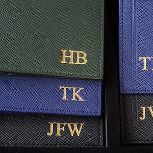K&ouml;nnte beinhalten: Vier Leder-Gep&auml;ckanh&auml;nger mit goldenen Buchstaben. Die Anh&auml;nger sind in verschiedenen Farben: gr&uuml;n, blau, schwarz und dunkelblau. Die Initialen auf den Anh&auml;ngern sind HB, TK, JFW und JW.