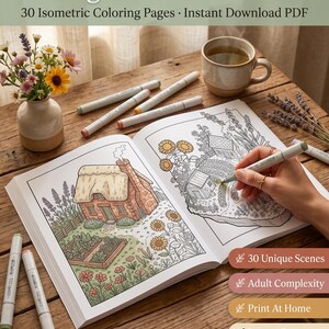 May include: A coloring book with a cottage scene is open on a wooden table, with a hand using a green marker to colour it. Other markers, a cup of tea, and flowers are also on the table. Text reads "Cottagecore Homestead" and "30 Isometric Coloring Pages".