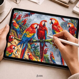 May include: A digital tablet displaying a pixel art illustration of multiple colorful macaws with red, yellow, and blue feathers perched on branches. The screen shows a grid-based design being edited with a white stylus, featuring vibrant tropical birds.