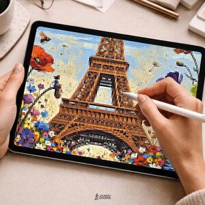 May include: A digital tablet displaying a pixel art illustration of the Eiffel Tower in Paris, surrounded by a vibrant field of colorful flowers including red poppies and blue blossoms, rendered in a blocky, mosaic-like style on the screen.
