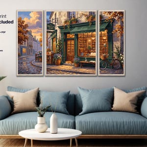 May include: A triptych wall art set depicting a European-style bookstore with a green storefront, a bicycle, and a cat. The text reads: Ready to print artwork included, High-resolution PNG + PDF sized for A3, Scalable SVG poster print up to 90 cm.