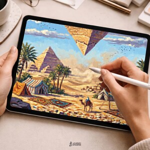 May include: A digital tablet displaying a pixel art illustration of an Egyptian desert landscape featuring pyramids, palm trees, tents, and a camel under a blue sky. The screen shows a vibrant scene with golden sand and geometric structures.
