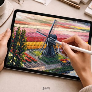 May include: A digital tablet displaying a pixelated landscape illustration featuring a dark windmill, a tall green tree, and a vibrant sunset sky with horizontal bands of pink, orange, and yellow colors, rendered in a distinct blocky mosaic style.