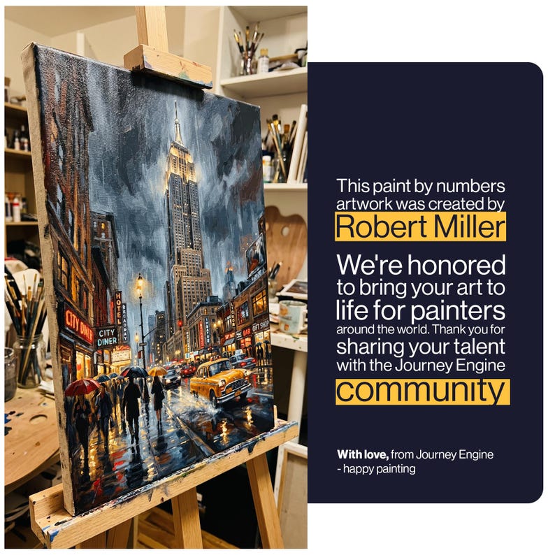 May include: A paint by numbers canvas on a wooden easel depicting a rainy New York City street scene with the Empire State Building, a yellow taxi, and pedestrians with umbrellas. Text reads: This paint by numbers artwork was created by Robert Miller.