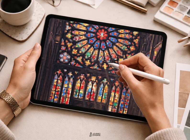 May include: A tablet displaying a digital pixel art illustration of a stained glass rose window and arched windows. The screen shows a vibrant mosaic of red, blue, yellow, and green squares arranged to form intricate architectural patterns.