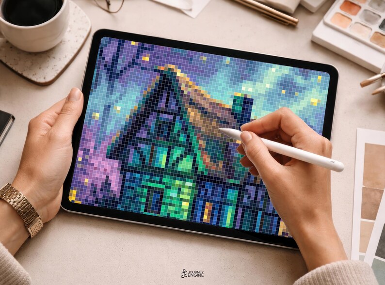 May include: A tablet displaying a pixel art illustration of a house with a steep roof, rendered in shades of blue, green, and purple. The digital artwork features a grid-like texture, with a stylus held over the screen to edit the vibrant, colorful scene.