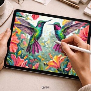 May include: A tablet screen displaying a pixel art illustration of two hummingbirds facing each other, surrounded by vibrant pink, orange, and yellow flowers. The digital artwork features a grid-like texture with a stylus held over the display.