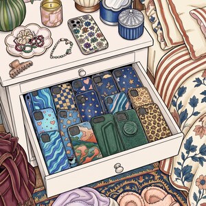 May include: A white bedside table with an open drawer containing a collection of patterned mobile phone cases. The surface of the table features a lamp, a candle, a small mirror, a lidded pot, and a dish holding hair accessories and beaded bracelets.