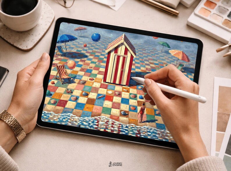 May include: A digital tablet displaying a pixelated beach scene with a central red and white striped beach hut, a checkered sand pattern, blue umbrellas, and a small figure. The screen shows a colorful mosaic-style artwork with a textured sea edge.