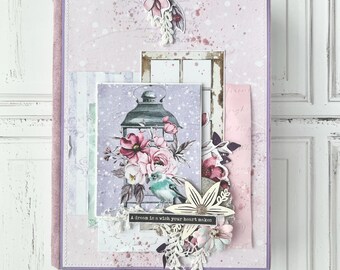 May include: A purple scrapbook with a pink and white floral design. The cover features a lantern with a bird and flowers, and the text "A dream is a wish your heart makes".