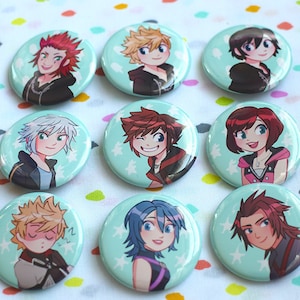 May include: Nine round buttons with cartoon character illustrations. Each button features a different character with varying hair colors and expressions. The buttons have a light blue background with white star accents, and are likely collectible items.
