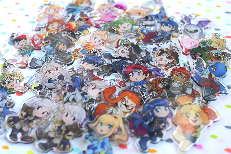 May include: A collection of colorful cartoon character keychains featuring characters from popular video games. The keychains are made of clear acrylic and feature a variety of characters, including Mario, Link, and Pikachu.