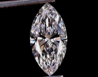 May include: A marquise-cut diamond held by tweezers against a black background. The diamond is clear and faceted, reflecting light. The elongated shape and brilliant cut create a sparkling effect, showcasing its clarity and brilliance.