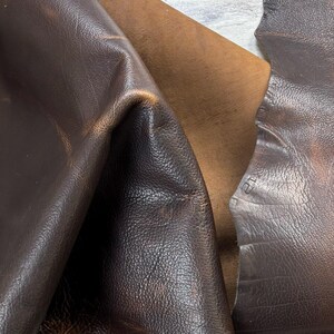 Puede incluir: Primer plano de tres piezas de cuero en diferentes tonos de marr&oacute;n. El cuero tiene una superficie texturizada con grano y pliegues visibles. Los colores var&iacute;an de un chocolate profundo y rico a un tono m&aacute;s claro, lo que sugiere diferentes procesos de curtido.