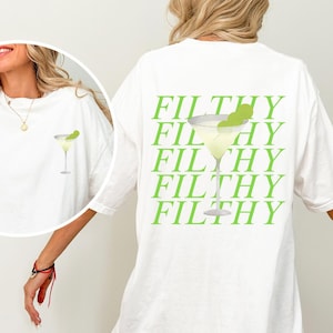 May include: White t-shirt with a margarita graphic on the front and back. The back features the word "FILTHY" repeated in green, with a margarita illustration. The front has a small margarita graphic.