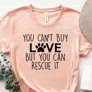 愛は買えないけど救えるシャツ、犬救出Tシャツ、犬愛シャツ、犬猫好きへのギフト、犬の足跡シャツ、ペットママTシャツ