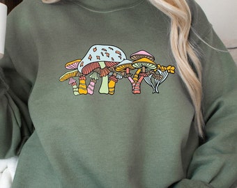 Könnte beinhalten: Ein grüner Pullover mit einem bunten Pilzmotiv. Die Pilze sind rosa, orange, gelb und grün.