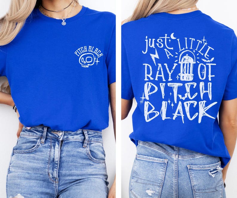 May include: Royal blue t-shirt with white graphic text and a skull design. The front of the shirt has the words "Pitch Black" with a skull graphic. The back of the shirt has the phrase "Just a Little Ray of Pitch Black".