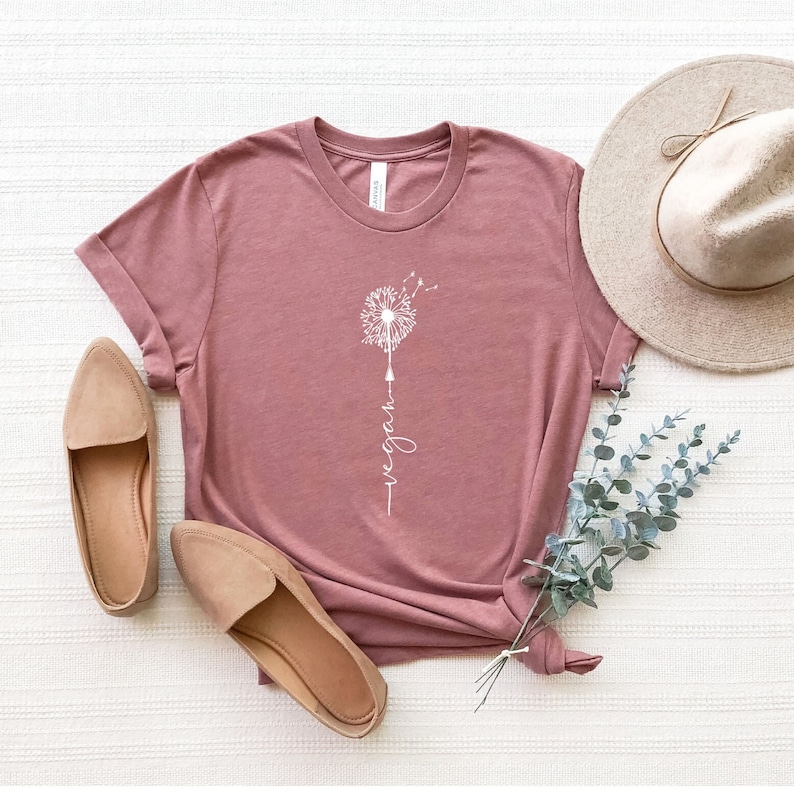 May include: A mauve t-shirt with a white dandelion graphic and the word "vegan" written vertically below it.