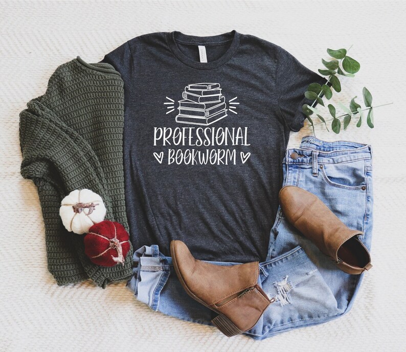 Peut inclure: Un t-shirt gris chin&eacute; fonc&eacute; avec un graphique de pile de livres et le texte "Professional Bookworm" en blanc.