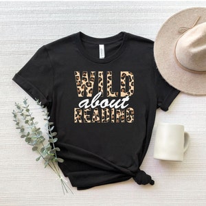 May include: Black t-shirt with a leopard print design that says "WILD about READING" in white text.