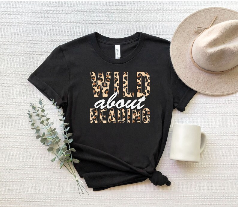 May include: Black t-shirt with a leopard print design that says "WILD about READING" in white text.