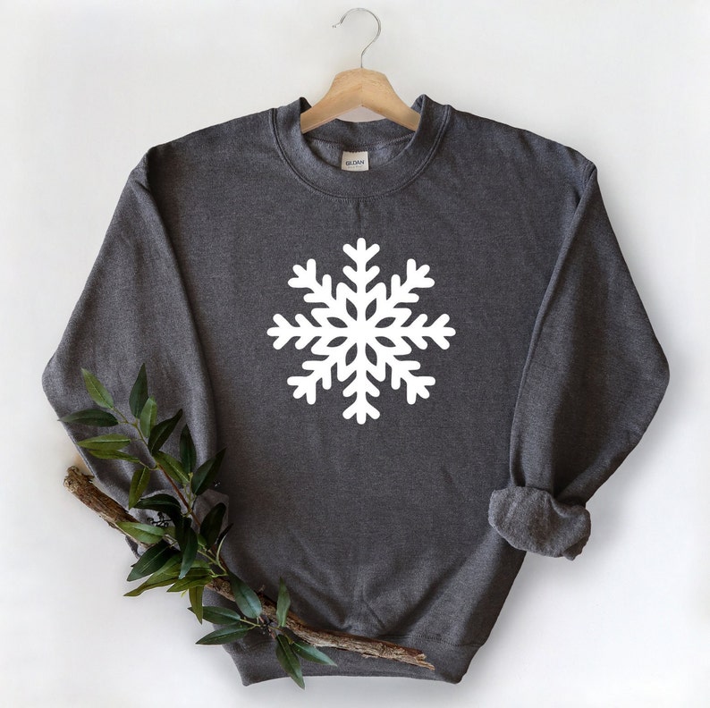 May include: A dark gray sweatshirt with a white snowflake design on the front.