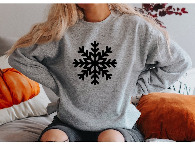 May include: A gray sweatshirt with a black snowflake design on the front.
