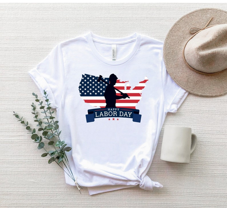 May include: White t-shirt with a graphic of a silhouette of a worker holding a hammer in front of an American flag in the shape of the United States. The text "Happy Labor Day" is printed below the graphic.