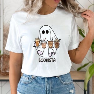 May include: White t-shirt featuring a ghost holding a selection of coffee drinks. The ghost has a friendly face and the text "Boorista" is printed below the ghost.