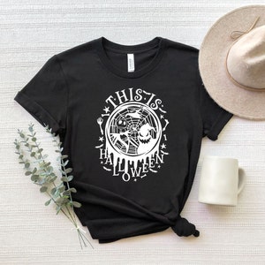 May include: Black t-shirt with a white graphic design featuring a spider web, a ghost, and the text "This is Halloween Love".