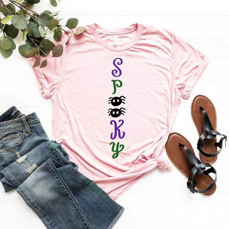 May include: Pink t-shirt with the word "Spooky" spelled vertically in green, purple, and black letters with two black spiders between the "O" and "K".