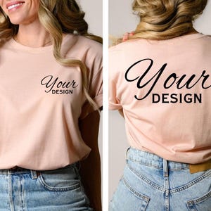 May include: A light pink t-shirt with the words "Your Design" printed on the front and back in a black script font. The shirt is paired with blue denim jeans.