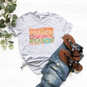 Puede incluir: Una camiseta gris con el texto "Everything Happens For A Reason" en una fuente retro con flores coloridas y caritas sonrientes. El texto "Take It One Day At A Time" est&aacute; impreso debajo del texto principal.