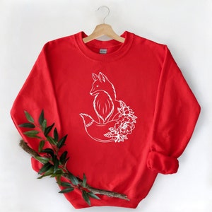 May include: Red sweatshirt with a white outline of a fox with flowers around its tail.