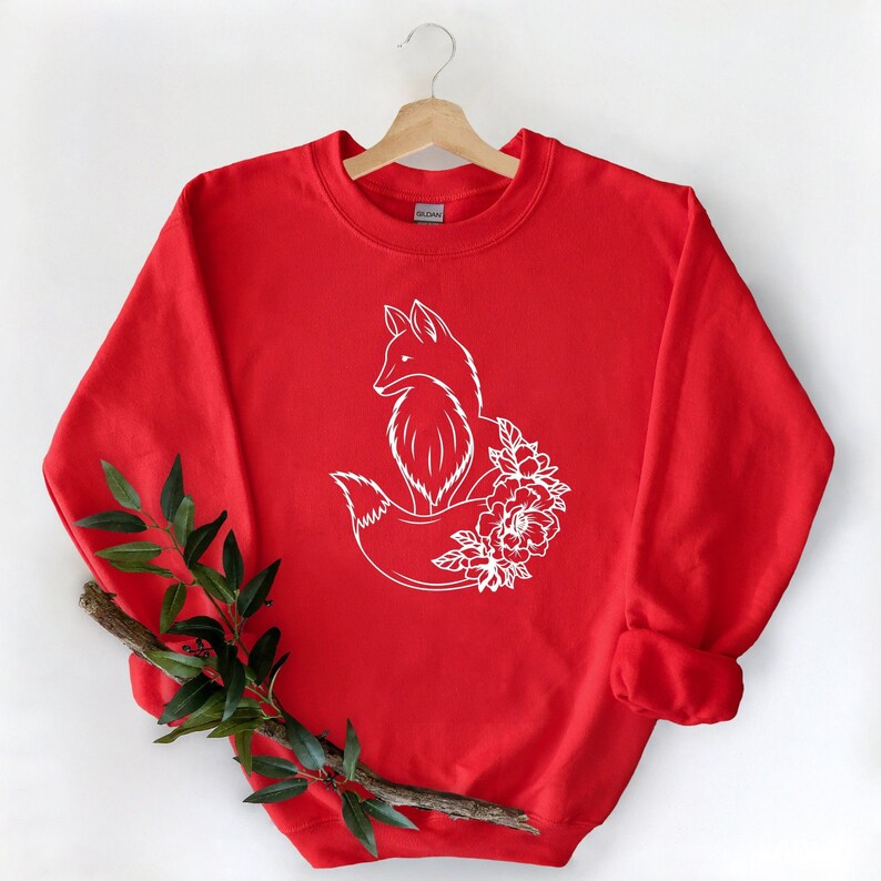 May include: Red sweatshirt with a white outline of a fox with flowers around its tail.