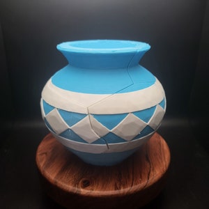 May include: A blue and white ceramic pot with a diamond pattern. The pot is cracked and has a rough texture.