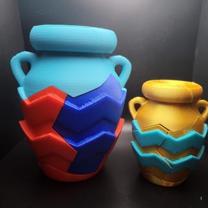 May include: Two ceramic puzzle jars, one blue and one gold, with a blue and red geometric pattern.
