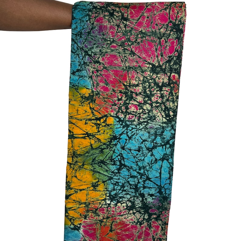 Puede incluir: Una tela colorida con un patr&oacute;n batik en tonos de azul, amarillo, rosa y verde. La tela tiene un fondo negro con un dise&ntilde;o blanco agrietado.
