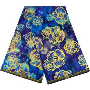 以下が含まれることがあります： 金色の花柄が施された青と紫の布地2枚。布地には金色の縁取りがあり、布地には「オリジナル」と「綿100％」の文字が印刷されています。