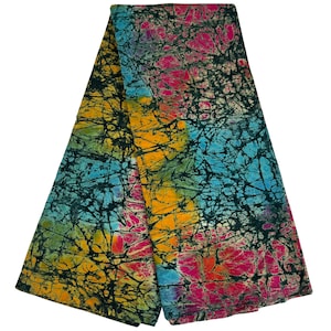 Puede incluir: Una tela batik colorida con fondo negro y un patr&oacute;n de l&iacute;neas azules, amarillas, rosas y verdes. La tela est&aacute; doblada por la mitad.