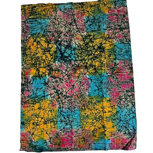 Puede incluir: Una tela colorida con un patr&oacute;n batik en tonos de azul, amarillo, rosa y verde. La tela tiene un fondo negro con un efecto craquelado.