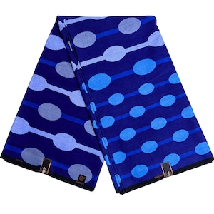 May include: A folded fabric featuring a repeating pattern of connected ovals and lines in shades of blue and white. The fabric has a dark blue background with lighter blue and white accents. The edges are finished with a black border.