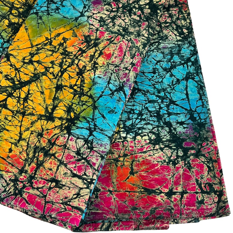 Puede incluir: Una tela colorida con un patr&oacute;n batik en tonos de azul, amarillo, rosa y negro. La tela tiene un efecto tie-dye y est&aacute; hecha de un material suave y ligero.